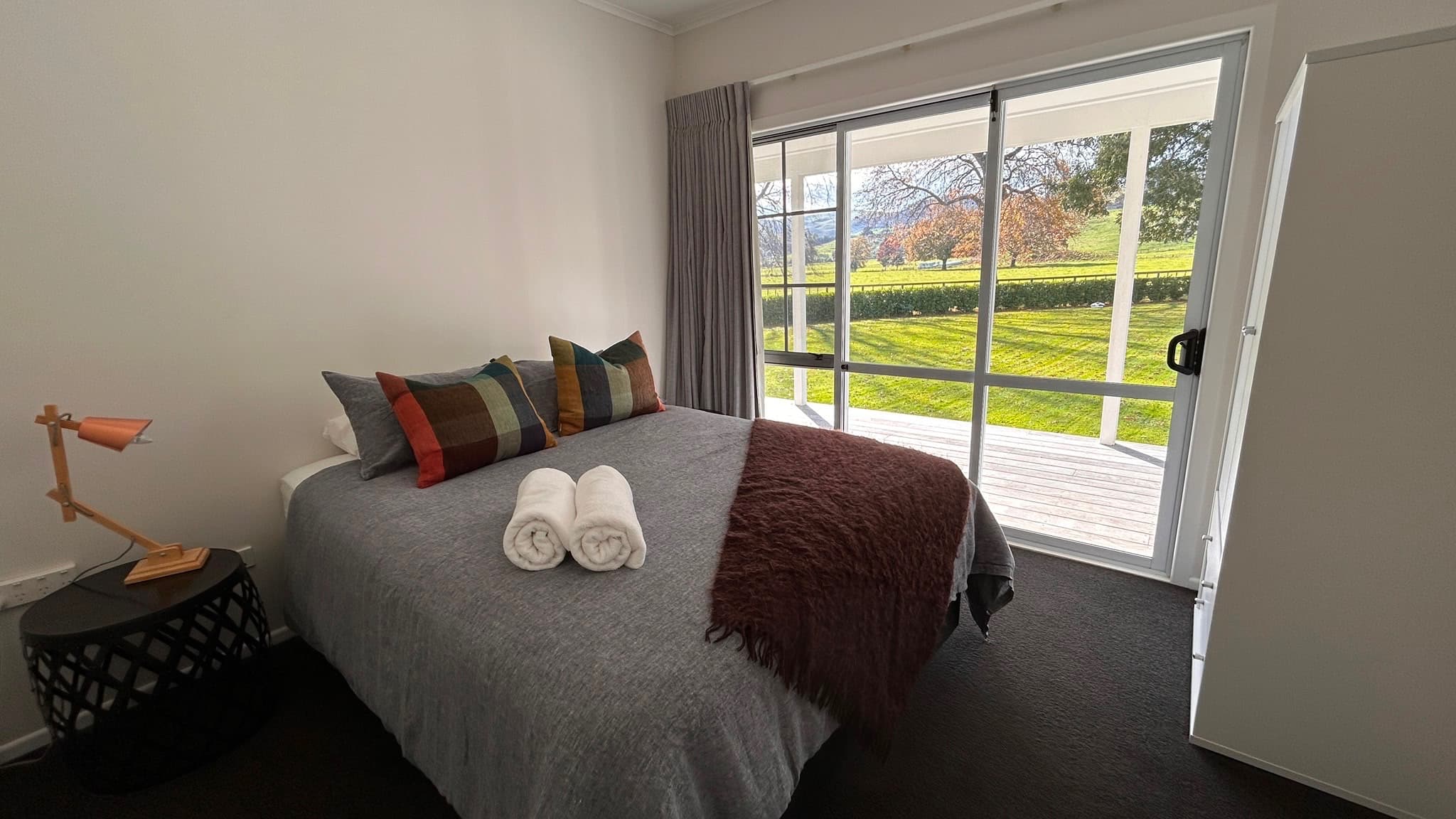 Queen bedroom with soft grey linen and deck outlook